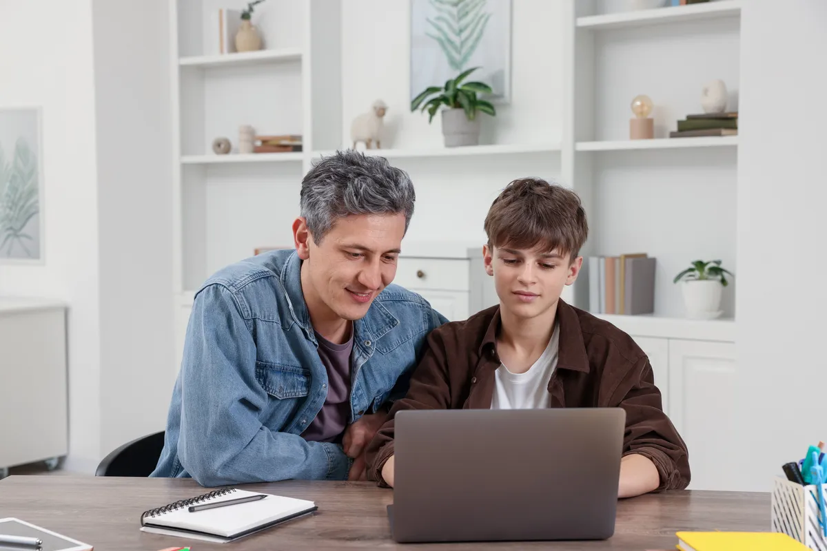 Parent and teen at home reviewing online school costs on a laptop
